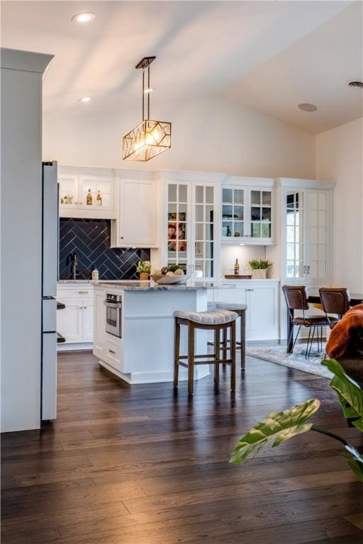 kitchen featuring dark hardwood / wood-style floors, white fridge, oven, decorative light fixtures, and white cabinets