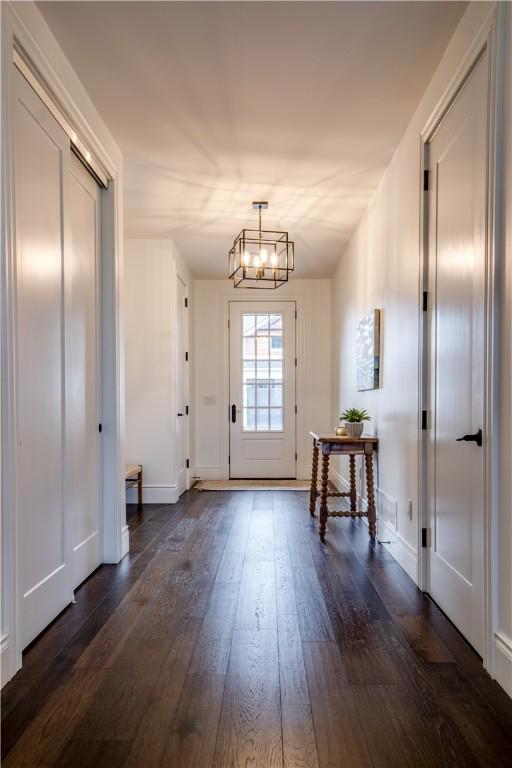 entryway with dark wood-type flooring and a notable chandelier