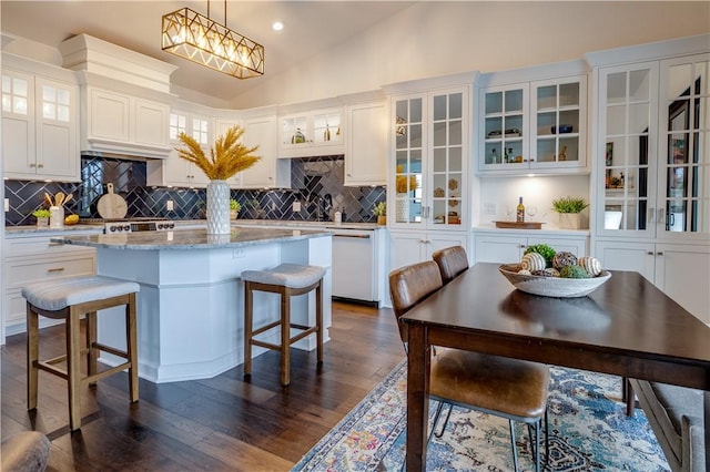 kitchen with a center island, white dishwasher, vaulted ceiling, decorative light fixtures, and white cabinets