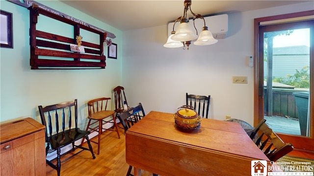 dining room featuring a notable chandelier, light wood-type flooring, and a wall unit AC