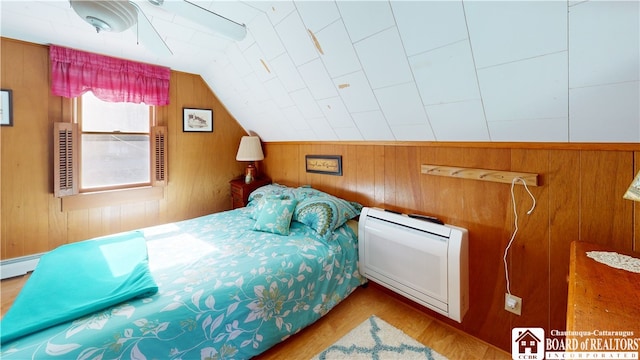 bedroom featuring wood walls, vaulted ceiling, and light wood-type flooring