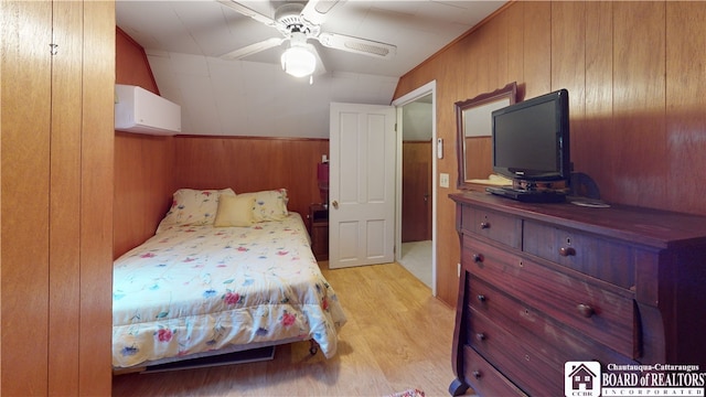 bedroom with a wall mounted air conditioner, lofted ceiling, ceiling fan, and light wood-type flooring