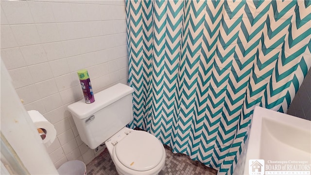 bathroom with tile walls, toilet, and tile flooring