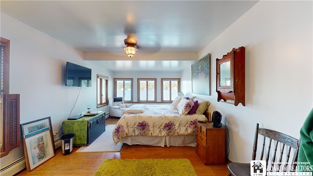 bedroom featuring light wood-type flooring, ceiling fan, and a baseboard heating unit