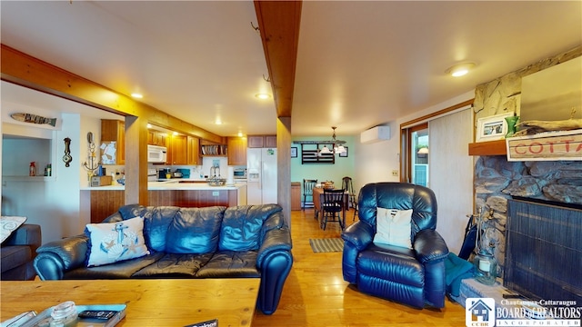 living room featuring a fireplace, a wall mounted AC, a chandelier, and light hardwood / wood-style floors