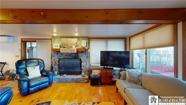 living room with a fireplace, an AC wall unit, beam ceiling, and light hardwood / wood-style floors