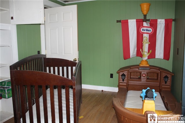 bedroom with a nursery area and dark wood-type flooring