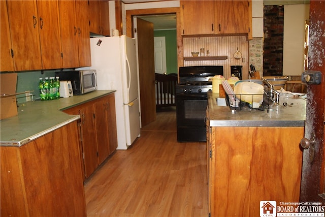 kitchen featuring light hardwood / wood-style flooring, brick wall, and black range with gas stovetop