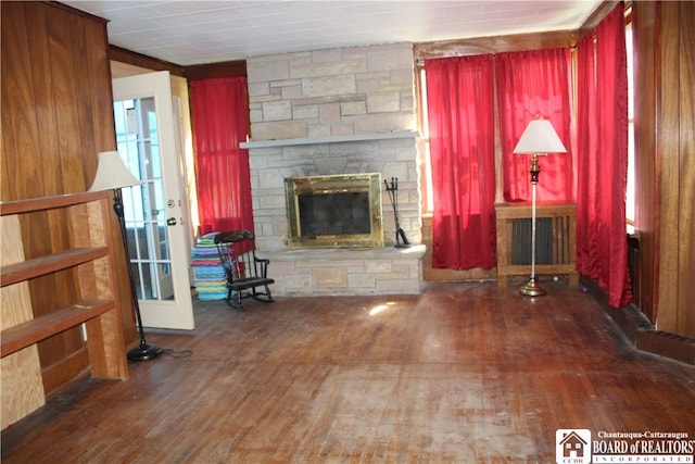 unfurnished living room with dark hardwood / wood-style floors, a stone fireplace, and radiator heating unit