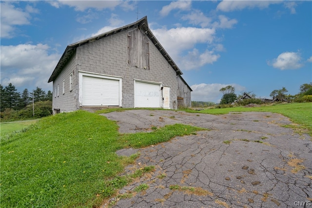 view of side of property featuring a garage and a lawn