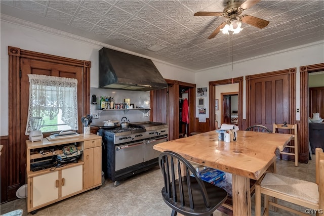 kitchen featuring ceiling fan, crown molding, light tile flooring, wall chimney exhaust hood, and range with two ovens