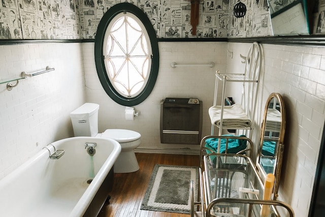 bathroom with tile walls, hardwood / wood-style flooring, and a bath to relax in