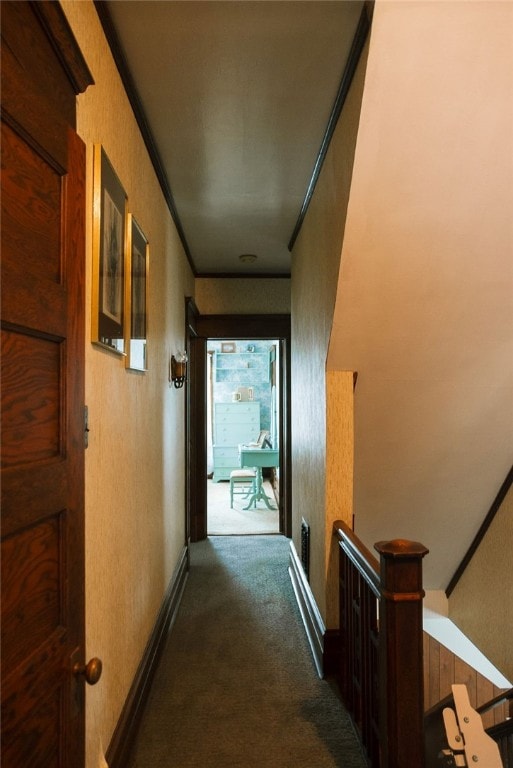 corridor with crown molding and dark colored carpet