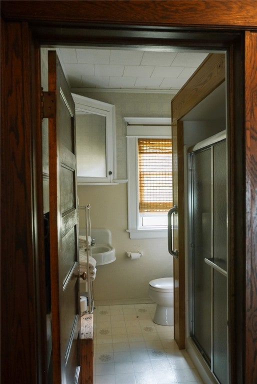 bathroom featuring a shower with shower door, tile flooring, and toilet