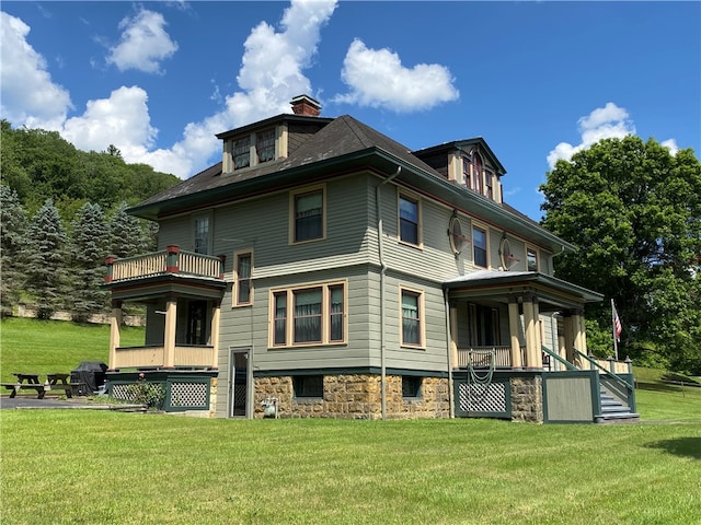 back of property featuring a balcony, a porch, and a lawn