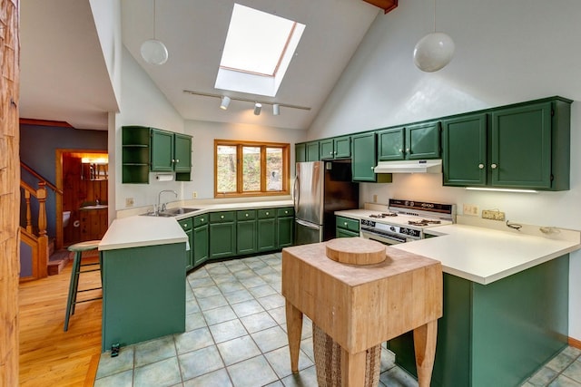 kitchen featuring stainless steel fridge, a notable chandelier, a skylight, sink, and range with gas cooktop