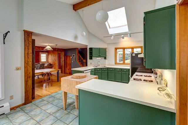 kitchen with black fridge, a skylight, light tile floors, sink, and hanging light fixtures