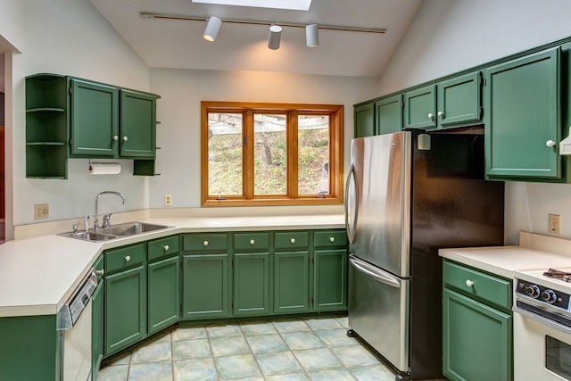 kitchen featuring appliances with stainless steel finishes, light tile flooring, track lighting, vaulted ceiling with skylight, and sink