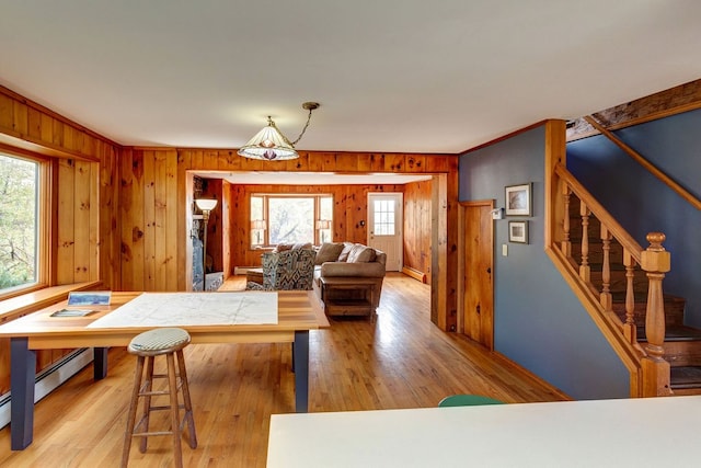 living room with a baseboard heating unit, wood walls, and light wood-type flooring