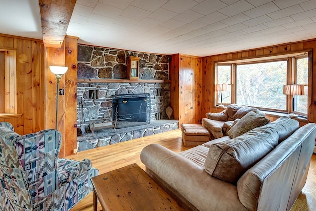 living room featuring wood walls, a stone fireplace, and wood-type flooring