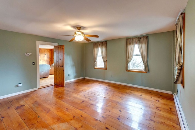 unfurnished room featuring ceiling fan, baseboard heating, and light hardwood / wood-style floors