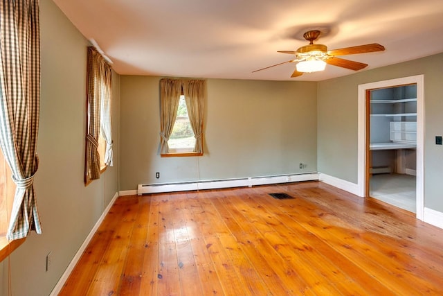 empty room featuring ceiling fan, light hardwood / wood-style floors, and a baseboard heating unit