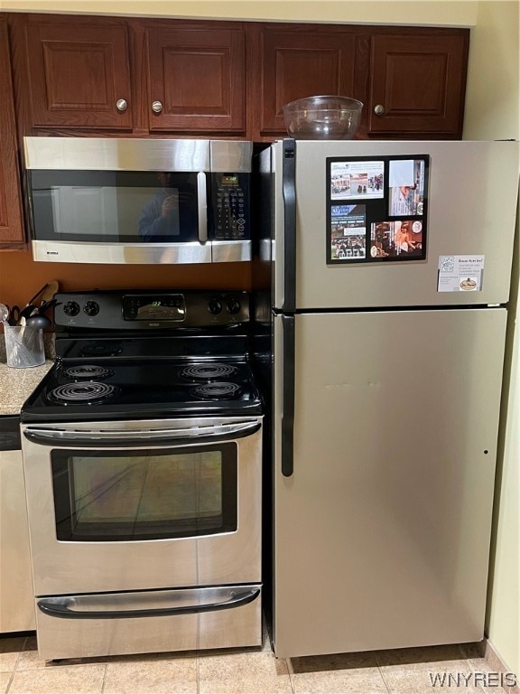 kitchen featuring light tile floors, appliances with stainless steel finishes, and dark brown cabinets