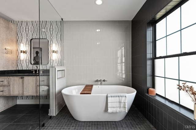 bathroom featuring a bath to relax in, tile walls, tile floors, and large vanity