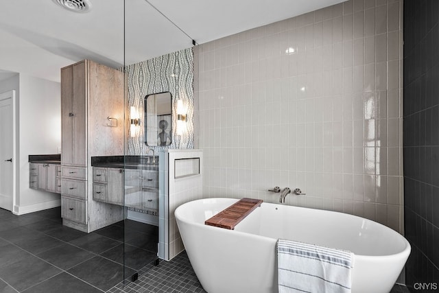 bathroom featuring tile walls, vanity with extensive cabinet space, a washtub, and tile floors