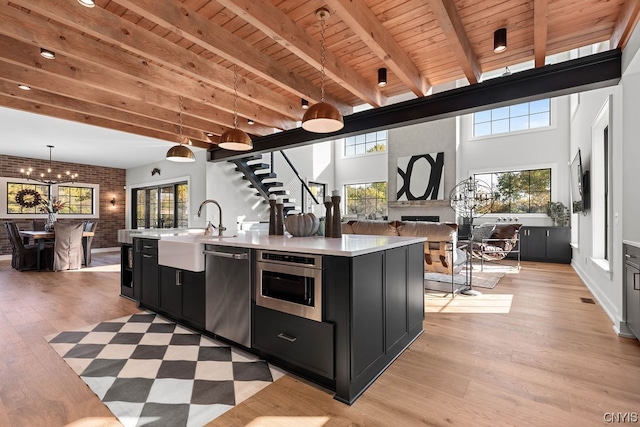 kitchen with pendant lighting, plenty of natural light, a kitchen island with sink, and wooden ceiling