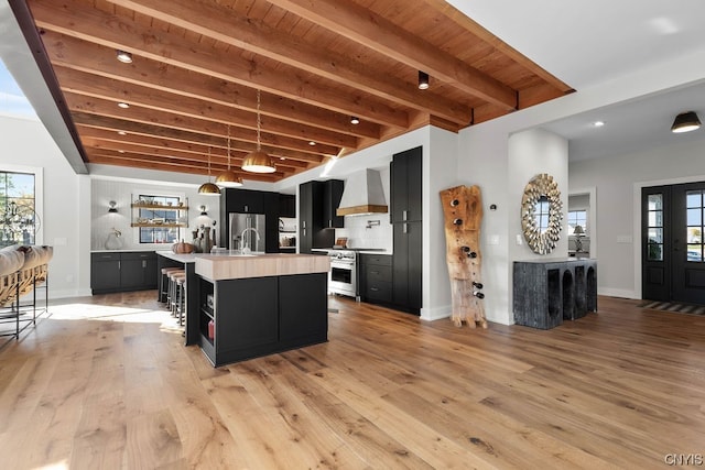 kitchen with light hardwood / wood-style floors, custom exhaust hood, backsplash, and beamed ceiling