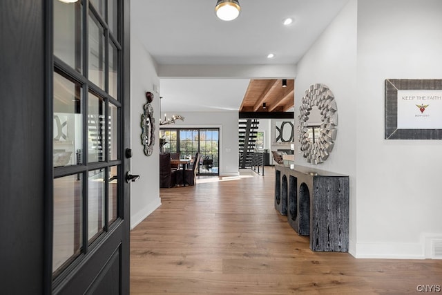 hallway with a chandelier, wood-type flooring, and beamed ceiling