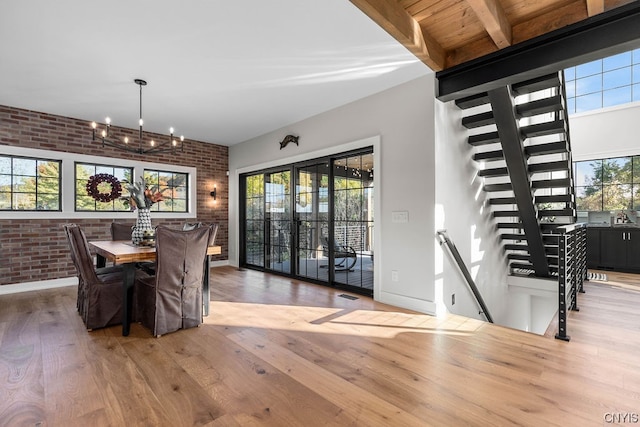 dining area with an inviting chandelier, brick wall, beamed ceiling, and hardwood / wood-style floors