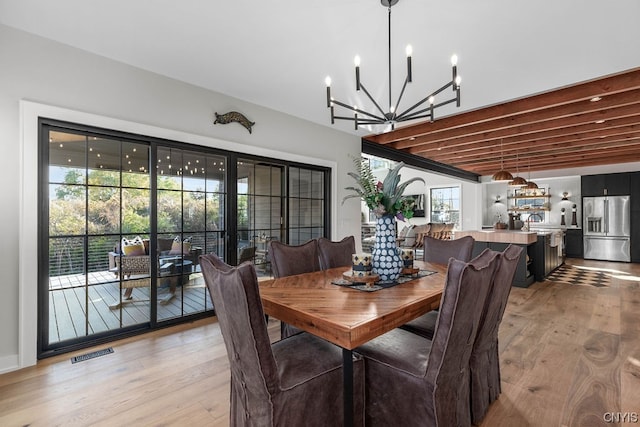 dining area with a notable chandelier, light hardwood / wood-style floors, and a healthy amount of sunlight