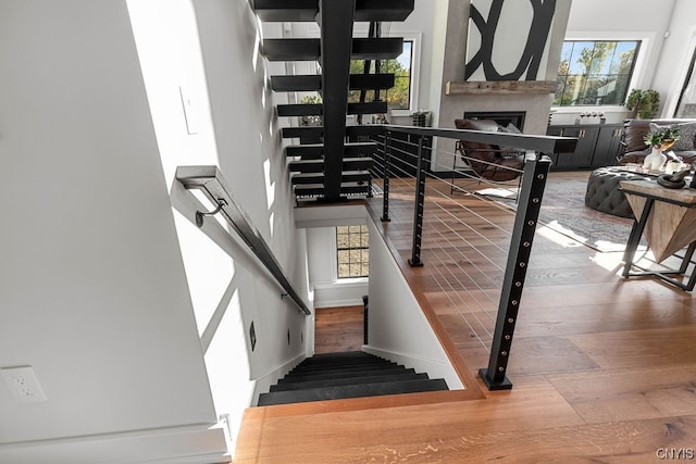 stairs with a towering ceiling, light wood-type flooring, and a wealth of natural light