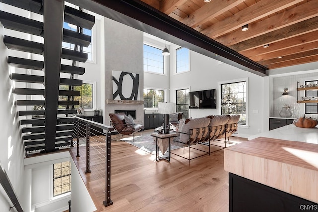 interior space with beamed ceiling, a high ceiling, light hardwood / wood-style floors, and wooden ceiling