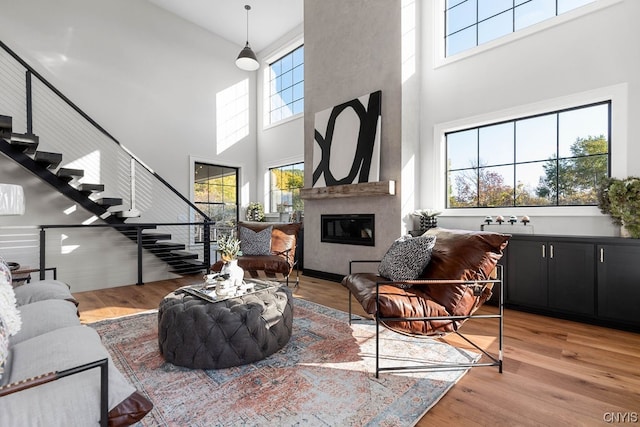 living room featuring a towering ceiling, light wood-type flooring, and a fireplace