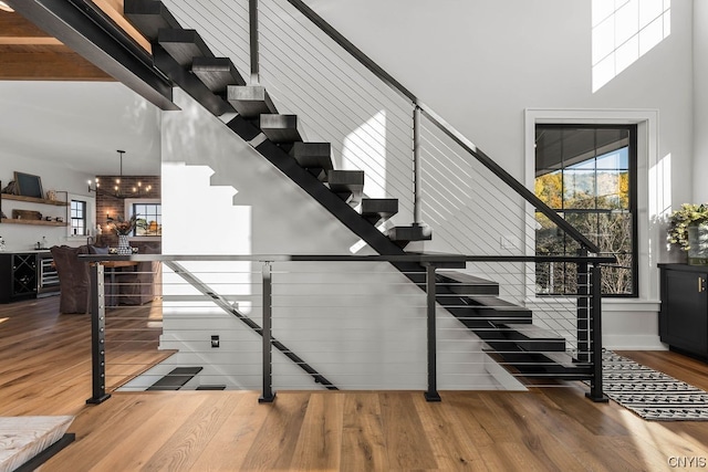 staircase featuring a notable chandelier, dark wood-type flooring, and a high ceiling