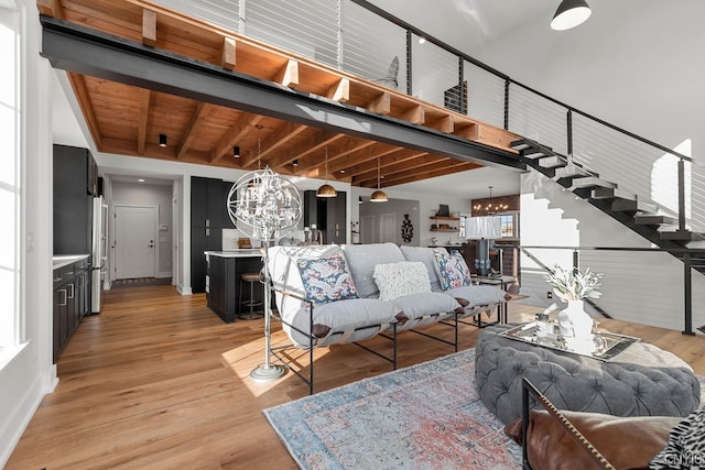 unfurnished living room featuring wooden ceiling, a notable chandelier, light hardwood / wood-style flooring, and beam ceiling