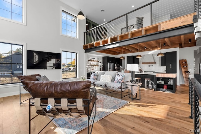 living room featuring light hardwood / wood-style floors, a towering ceiling, and a wealth of natural light