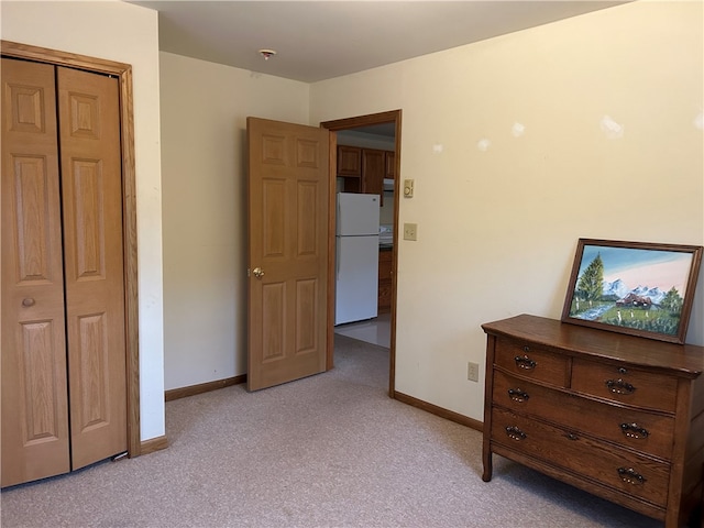 unfurnished bedroom with carpet flooring, white fridge, and a closet