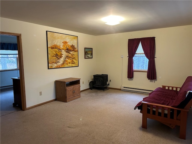 sitting room with a baseboard heating unit, a healthy amount of sunlight, carpet floors, and a wood stove