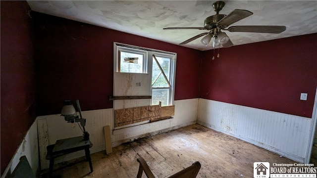 spare room with ceiling fan and wooden walls