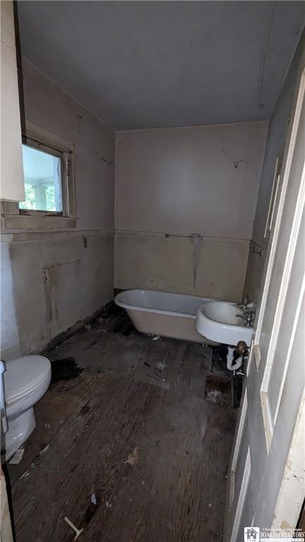 bathroom featuring hardwood / wood-style floors, sink, toilet, and a tub to relax in