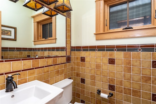 bathroom featuring tile walls, toilet, and sink