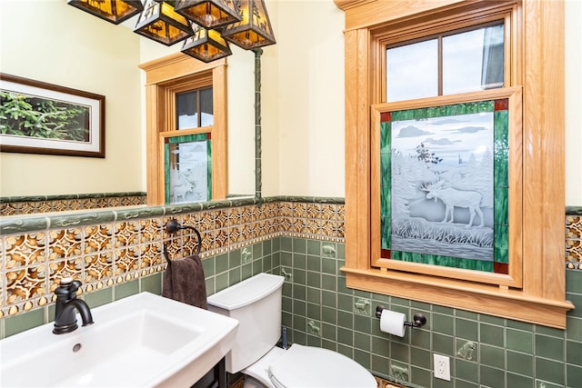 bathroom featuring tile walls, toilet, and sink