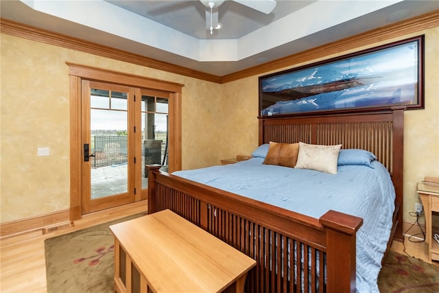 bedroom with wood-type flooring, a tray ceiling, crown molding, access to exterior, and ceiling fan