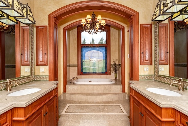 bathroom featuring tiled tub, an inviting chandelier, and vanity