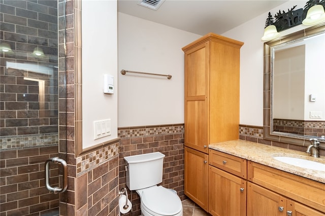 bathroom featuring toilet, a shower with door, vanity, decorative backsplash, and tile walls