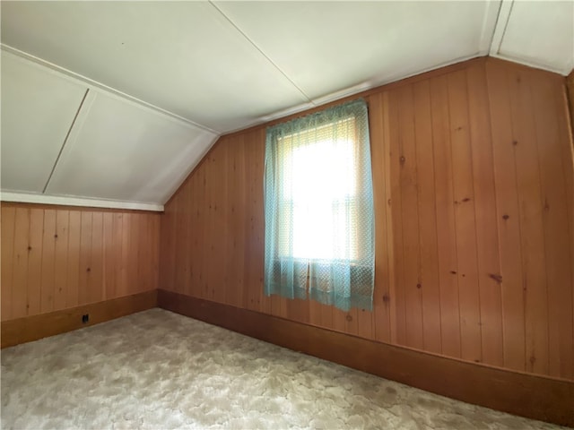 additional living space featuring wood walls, carpet, and lofted ceiling